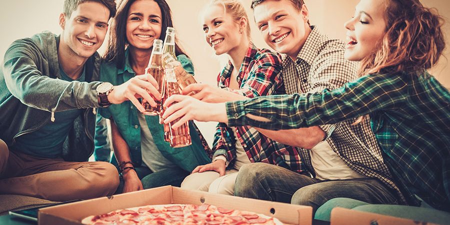 Imagen en la que se observa un grupo de personas tomando refrescos y compartiendo unas pizzas